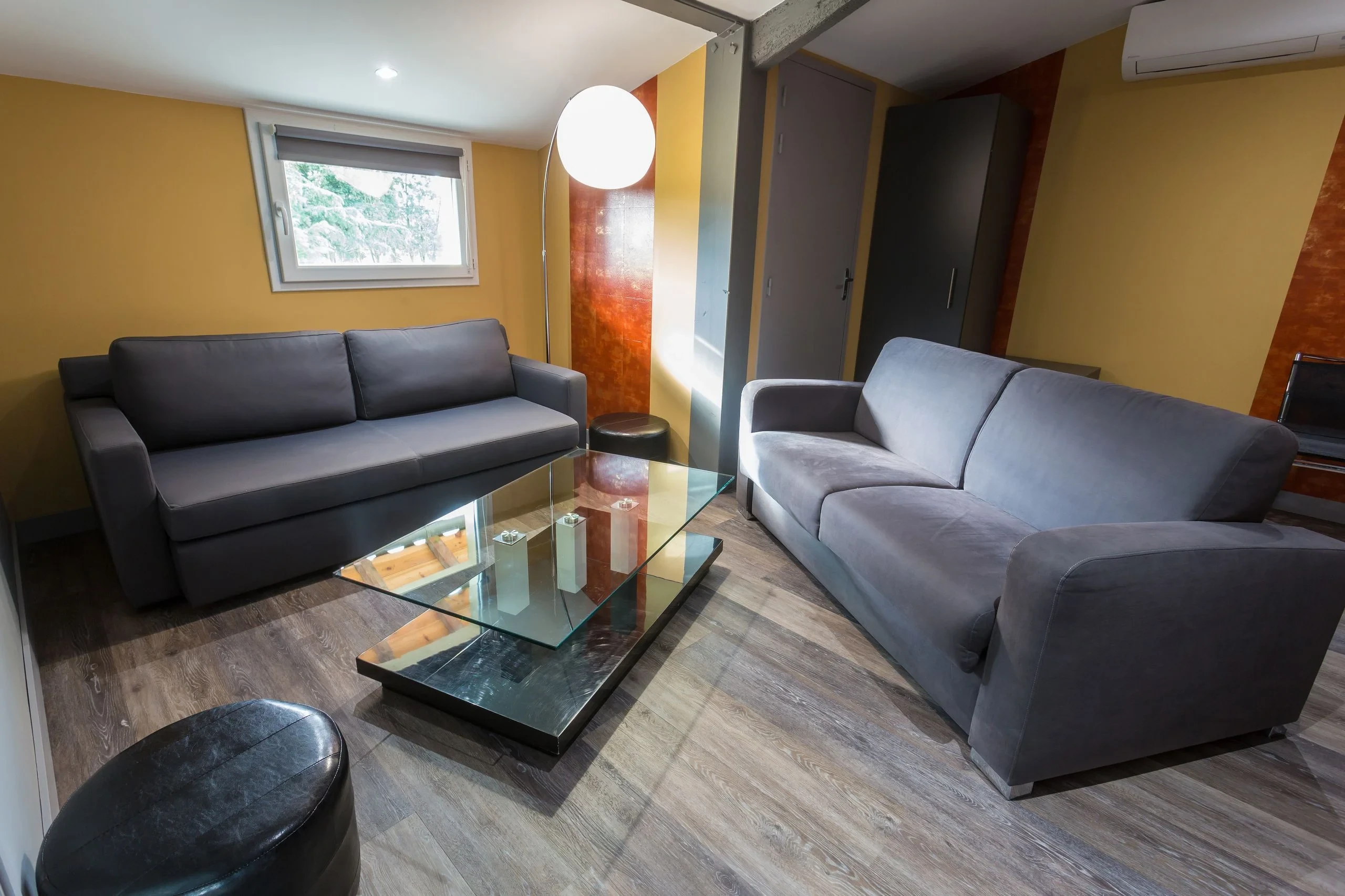 Salon moderne avec canapés gris et table en verre