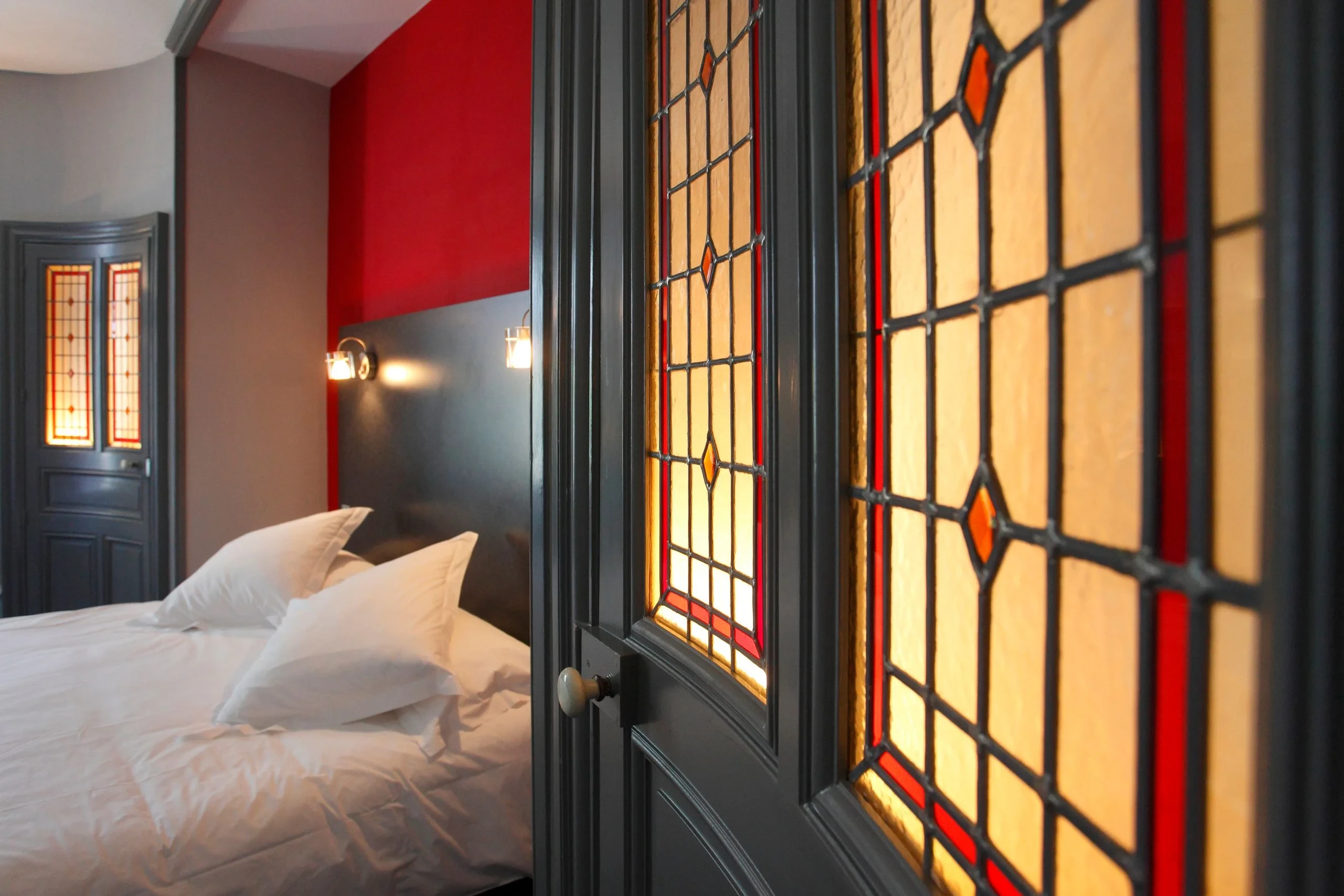 Chambre avec vitraux et mur rouge élégant