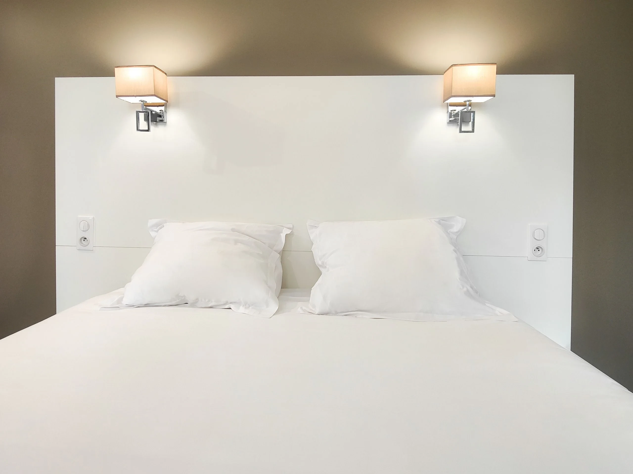 Lit blanc minimaliste avec deux lampes murales