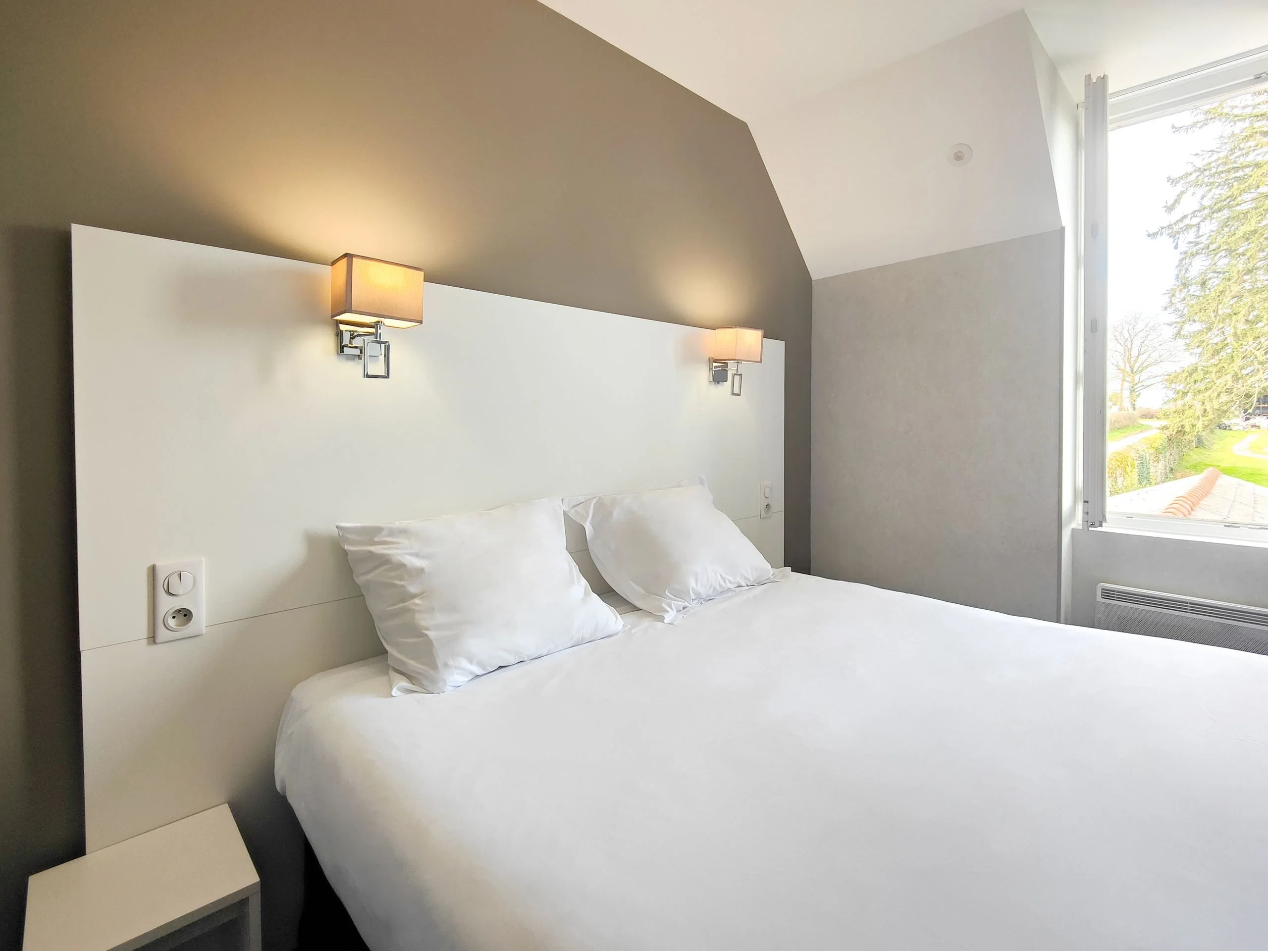 Chambre moderne avec lit double et fenêtre lumineuse