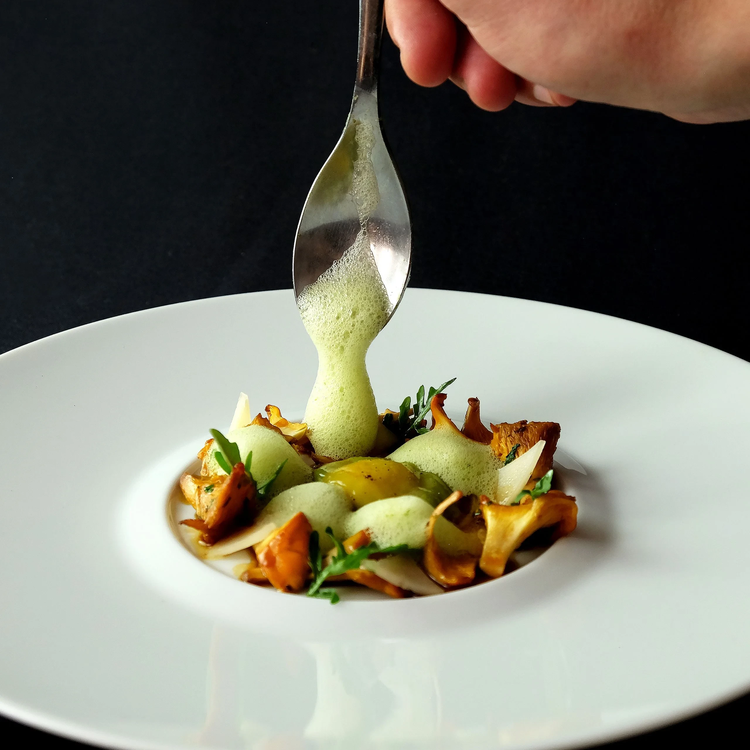 Mousse verte versée sur plat gastronomique aux girolles