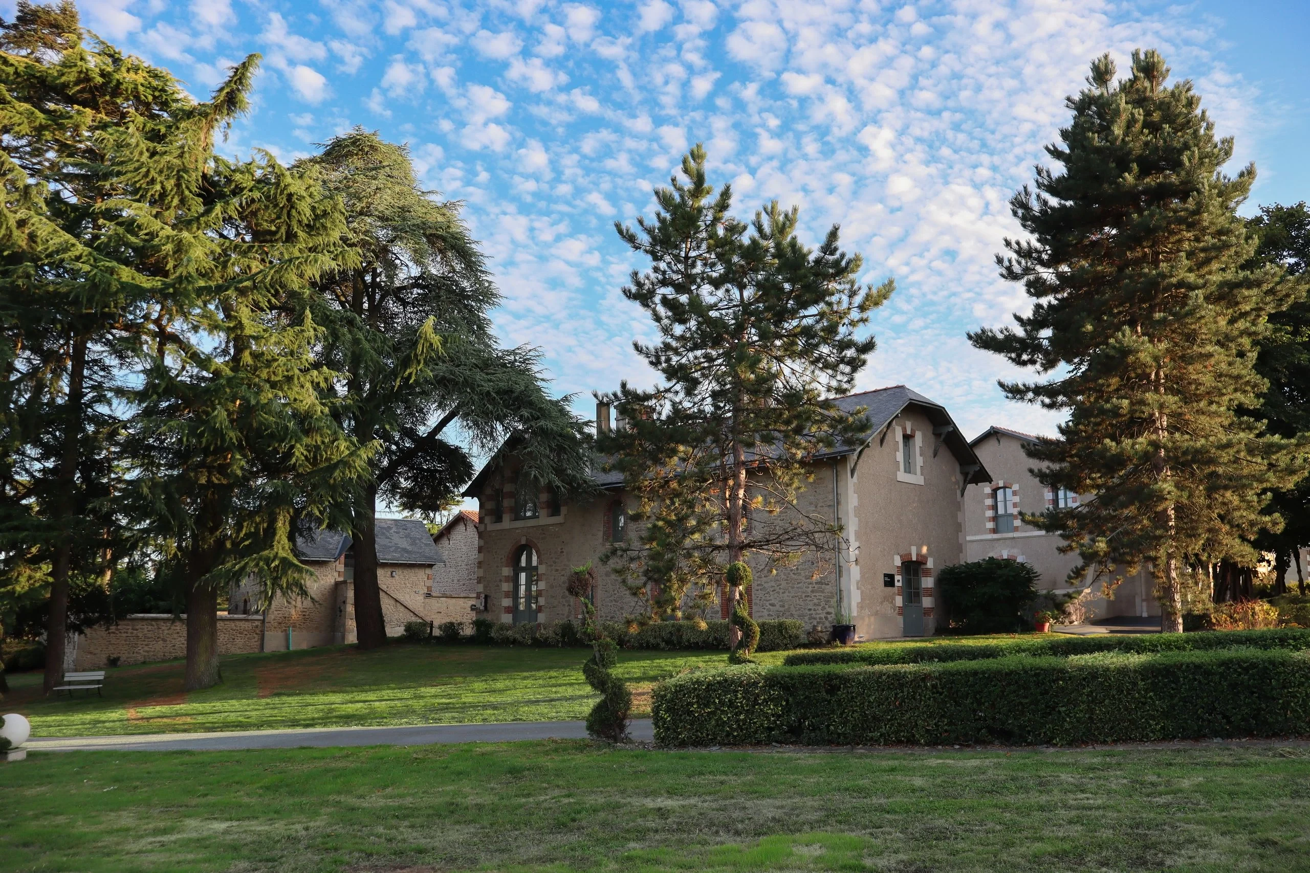 Maison en pierre entourée d’arbres et jardin