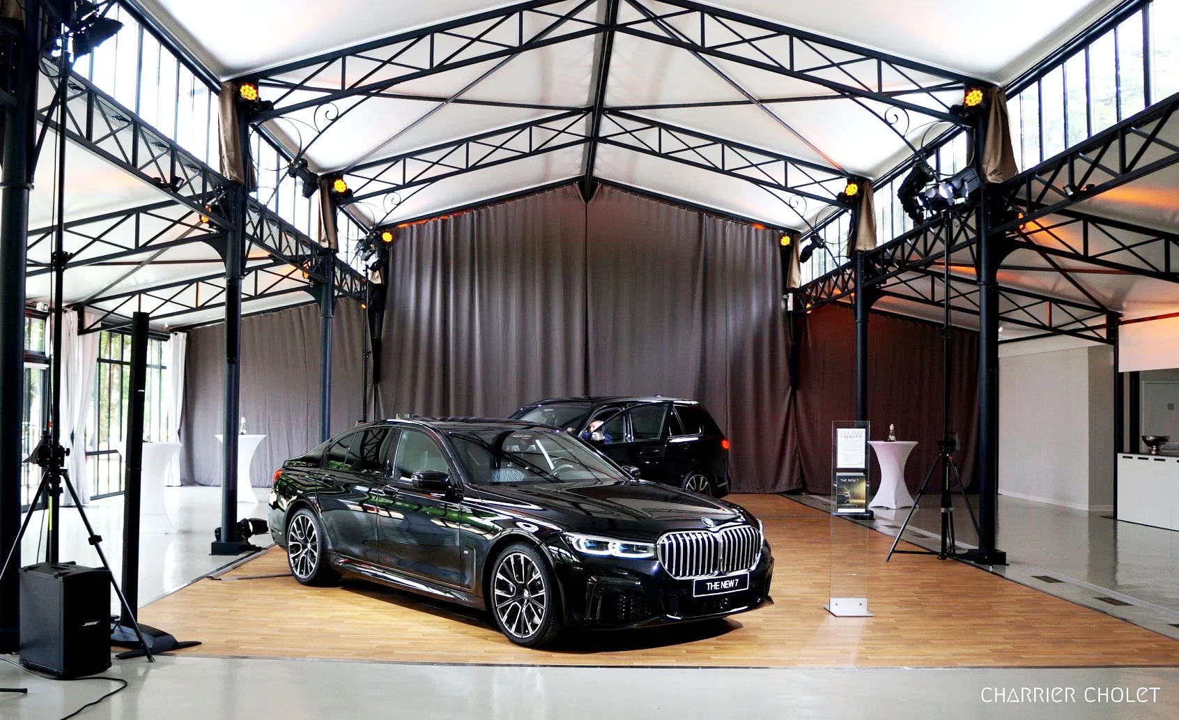 Berline BMW noire exposée en salle événementielle