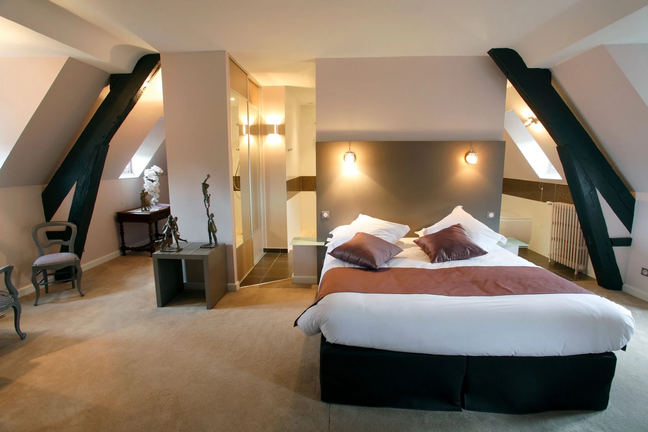 Chambre mansardée avec poutres apparentes et lit double