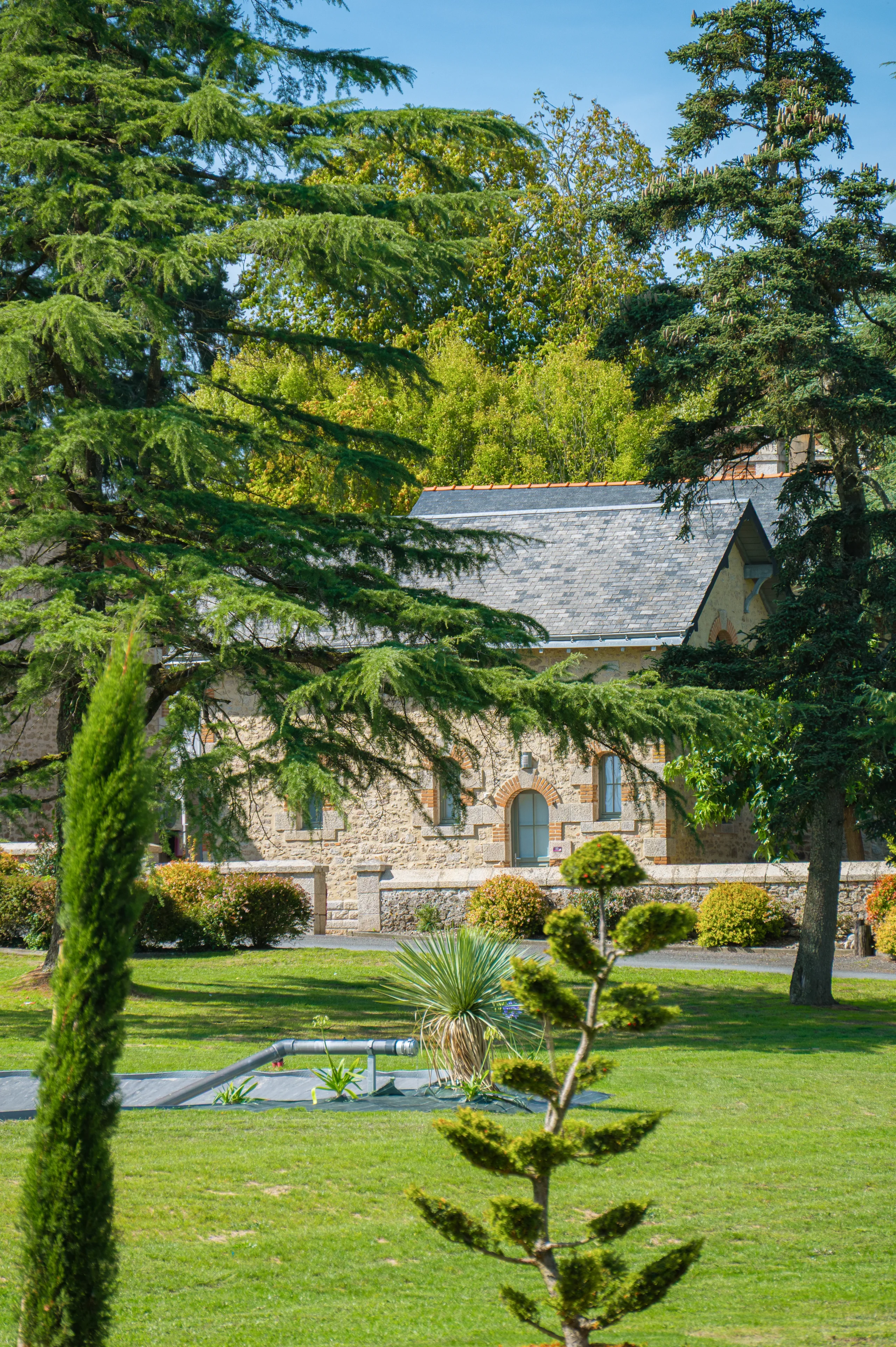 Maison en pierre entourée d’un jardin arboré