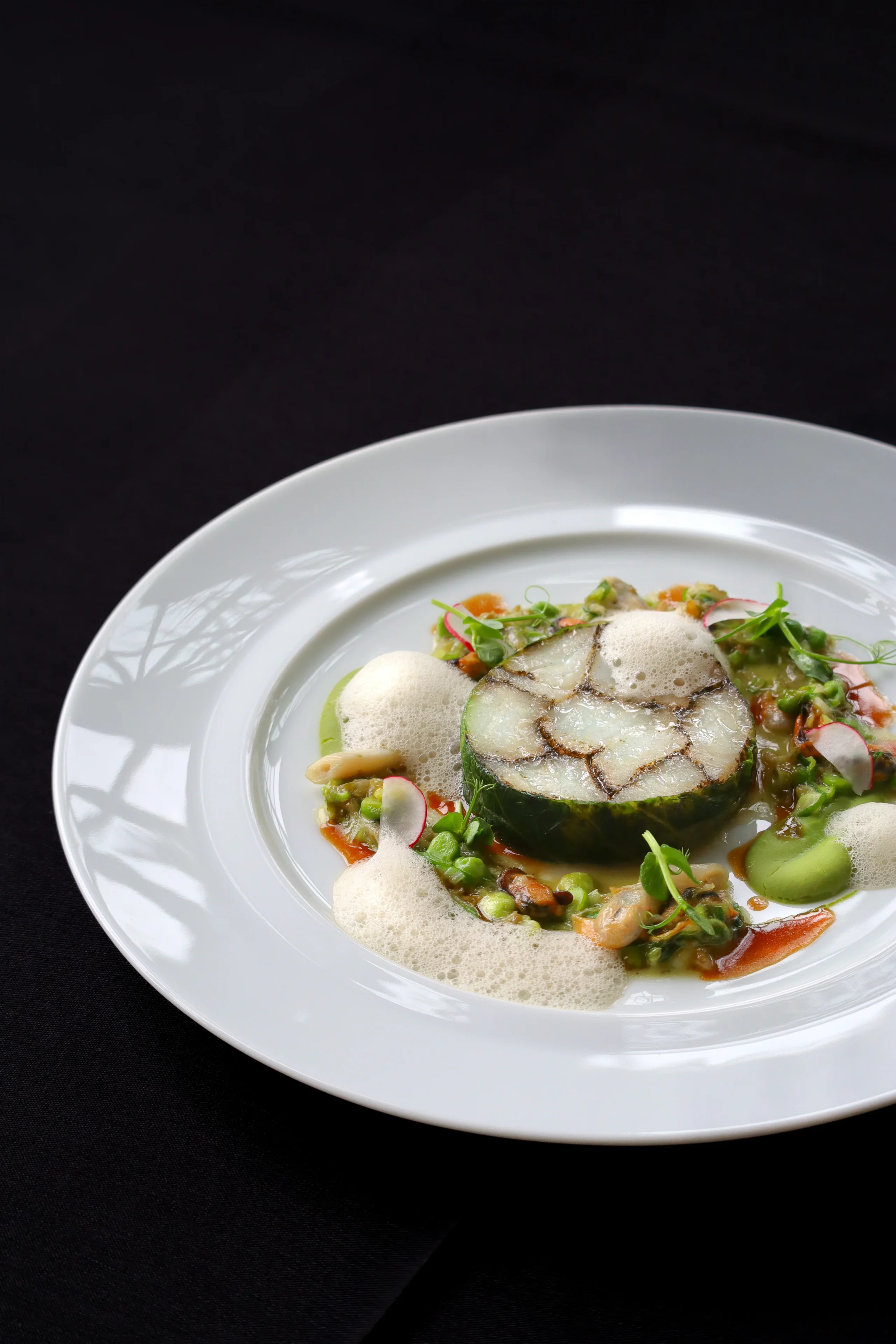 Plat gastronomique avec légumes, mousse et fruits de mer