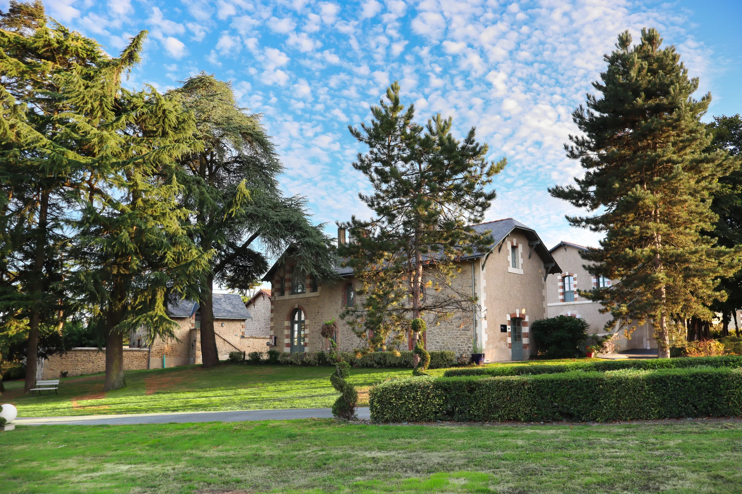 Maison en pierre entourée d’arbres et pelouse verdoyante