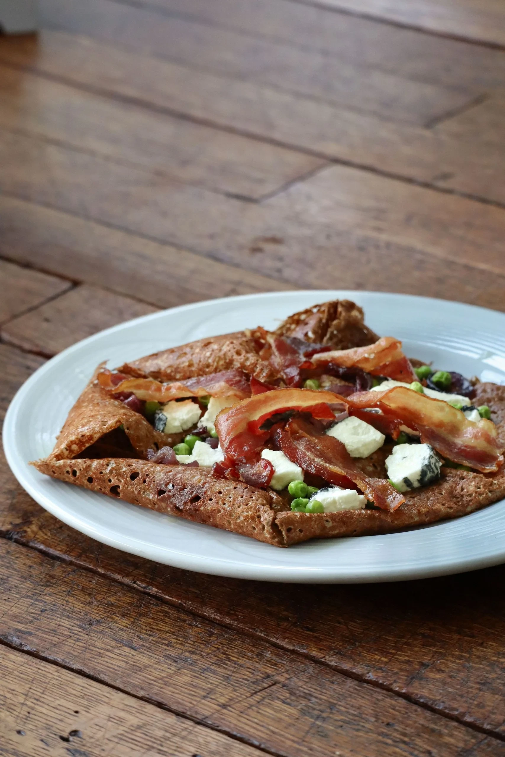 Galette garnie de lard, fromage et petits pois