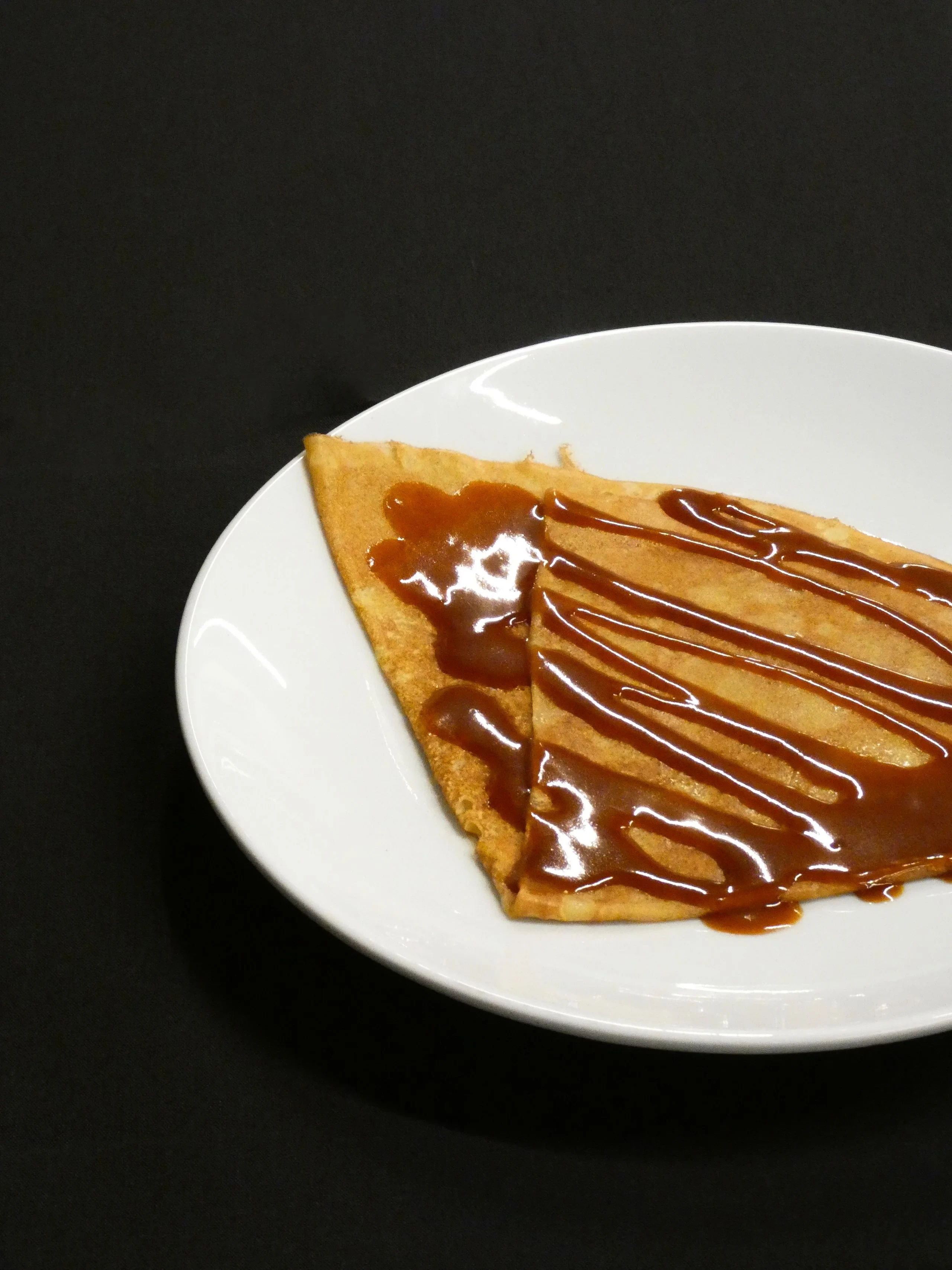 Crêpe pliée nappée de caramel sur assiette blanche