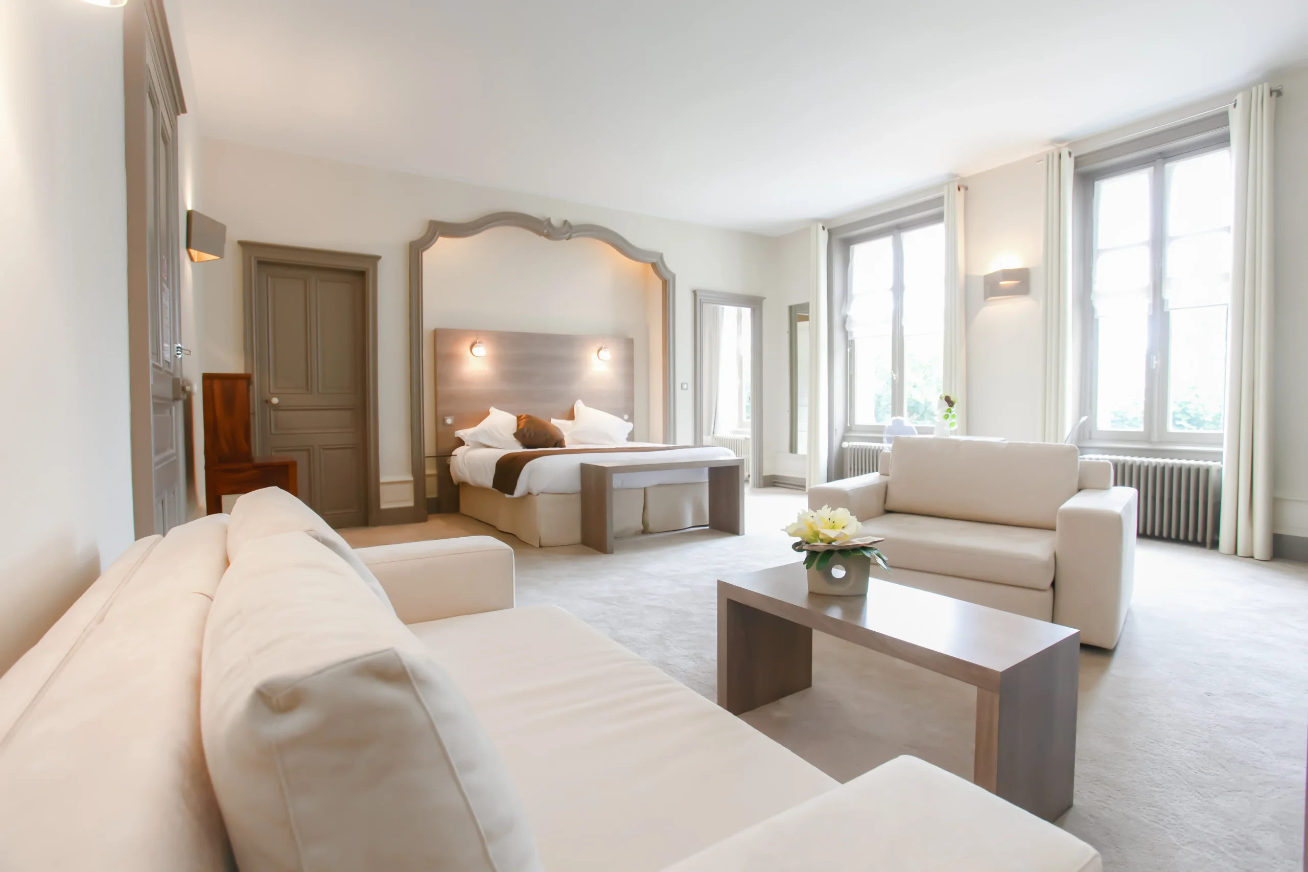 Chambre d’hôtel lumineuse avec lit et canapés